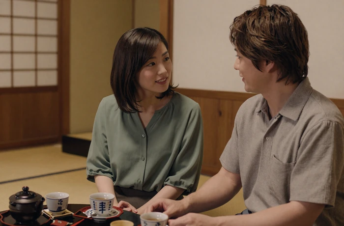 Western man and Japanese woman enjoying tea together at a traditional Japanese teahouse with warm intimate lighting