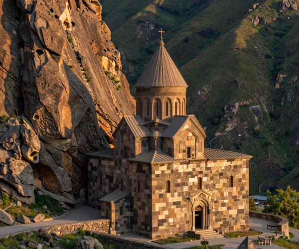 Ancient Armenian Geghard Monastery carved into mountain cliffs bathed in golden hour sunlight