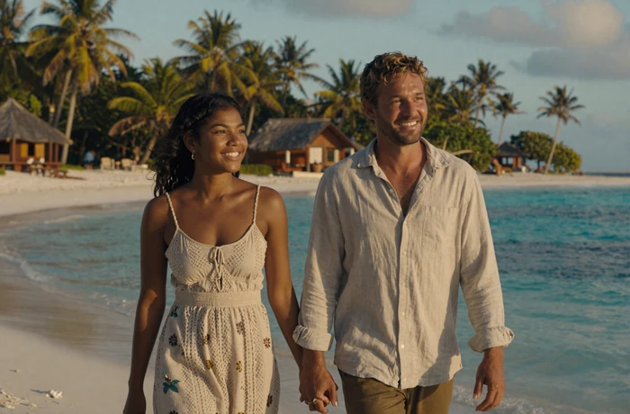 Western man and Timorese woman walking together on a tropical East Timor beach at golden hour